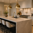 Modern luxury kitchen featuring a large marble waterfall island, brass pendant lighting, white cabinetry, and upscale contemporary finishes.